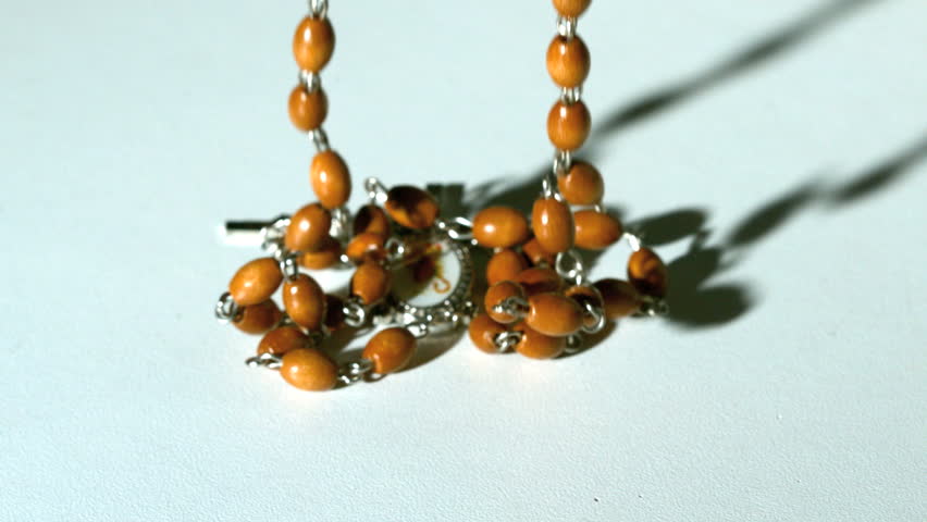Rosary beads casting a shadow and then falling in slow motion