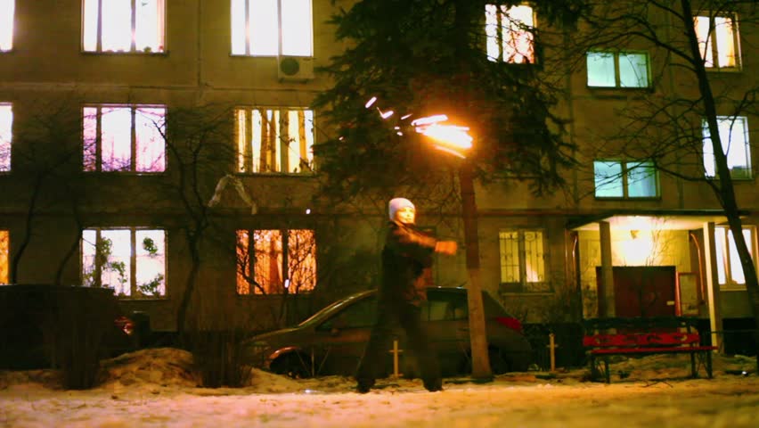 Young boy stands on yard and spins firework near dwelling house at night