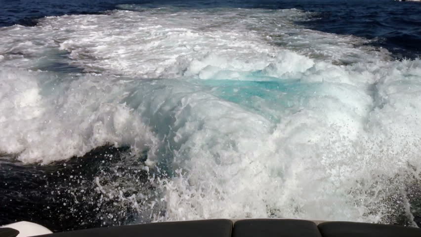view from stern of motor yacht cruising past larger super yacht anchored off Monaco
