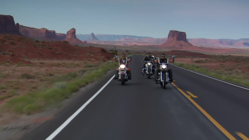 Three bikers on a winding open desert highway