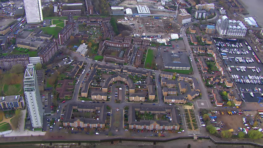 Aerial view over a London district, showing residential tower blocks and other housing, as well as green spaces and roads and other industrialised  areas.