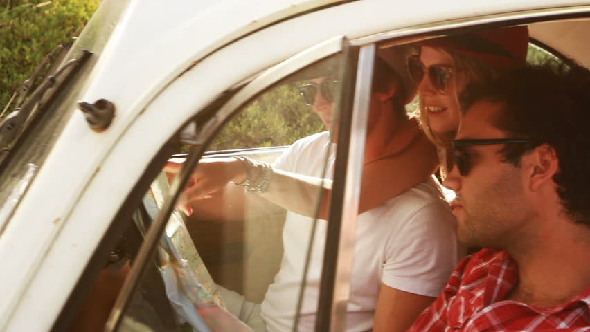 Young Hipster friends on a roadtrip looking at a map.