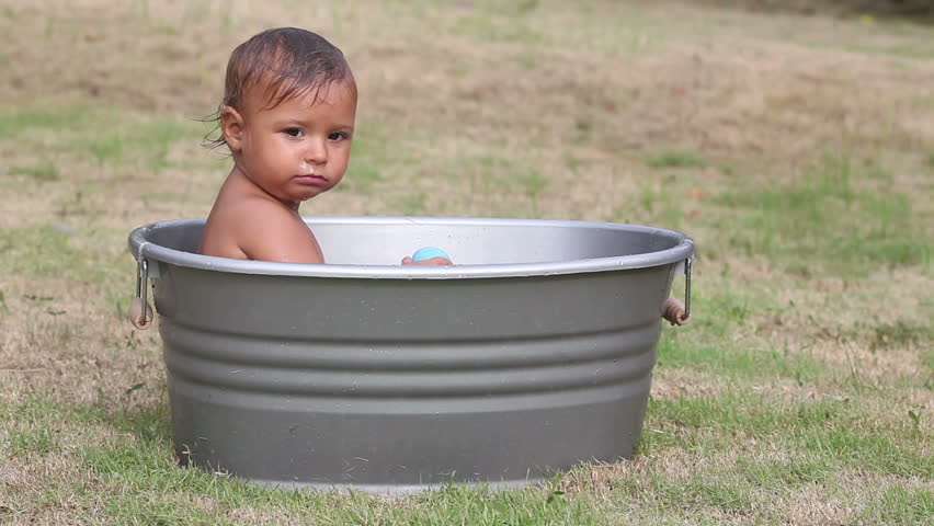 Happy pretty small girl sitting in washbowl outdoor