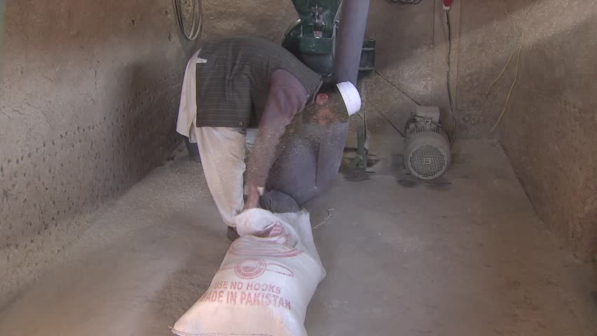 Village in Upper Yaftal, Afghanistan - November 9, 2010:  Miller filling a sack with flour in his mill in remote north-east Afghanistan.