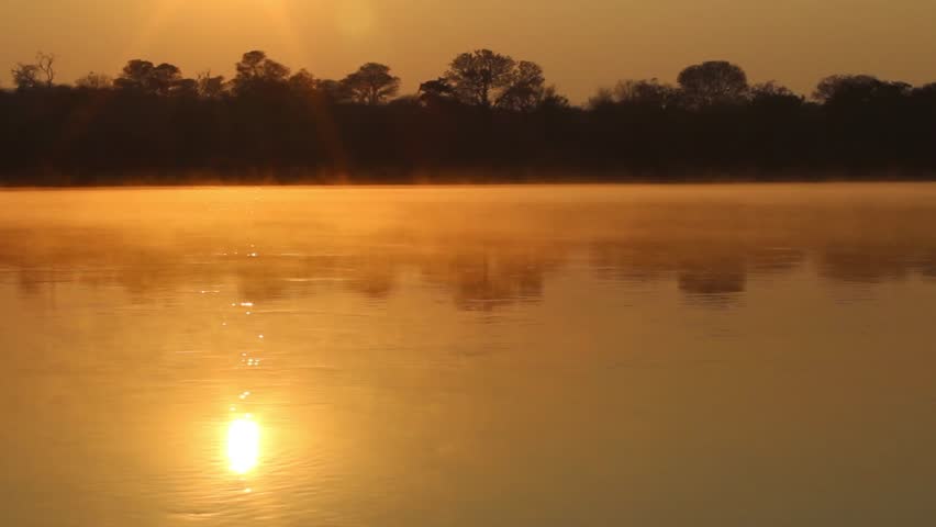 Sunrise reflex at Kavango river whit mist on the water surface, Caprivi region. Namibia