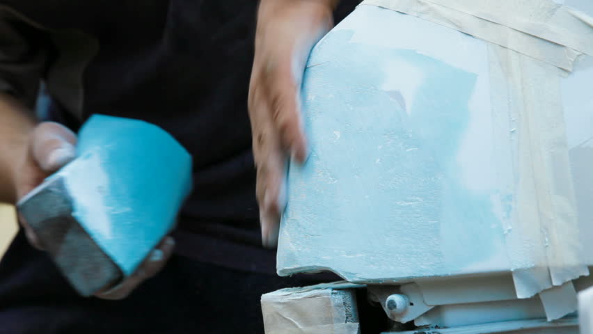 Repairman is preparing car surface for smearing putty, wiping it with a cloth.