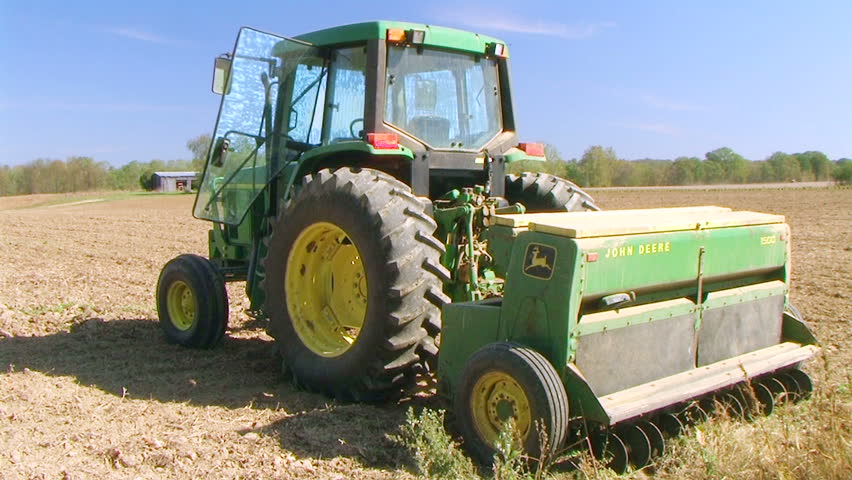 Farmer sowing wheat crop using a tractor and seeder. 