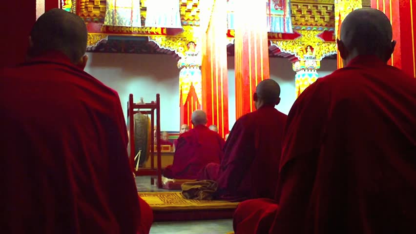 A group of monks sit and chant prayers in a monastery high in the Himalayas.
