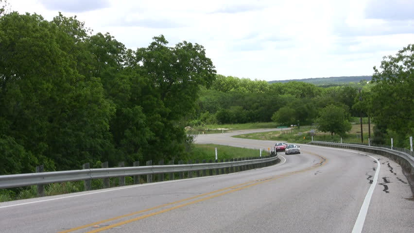 Video of two small sports cars driving close together towards camera. Winding country road. Red and silver color automobiles. Don Despain of Rekindle Photo.