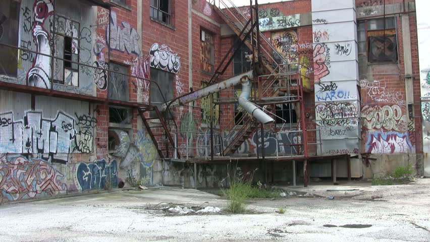 Video of old abandoned building covered with graffiti. Commercial equipment and stairs painted by vandals. Destruction of private property. Zoom in. Wind blowing weeds. Don Despain of Rekindle Photo