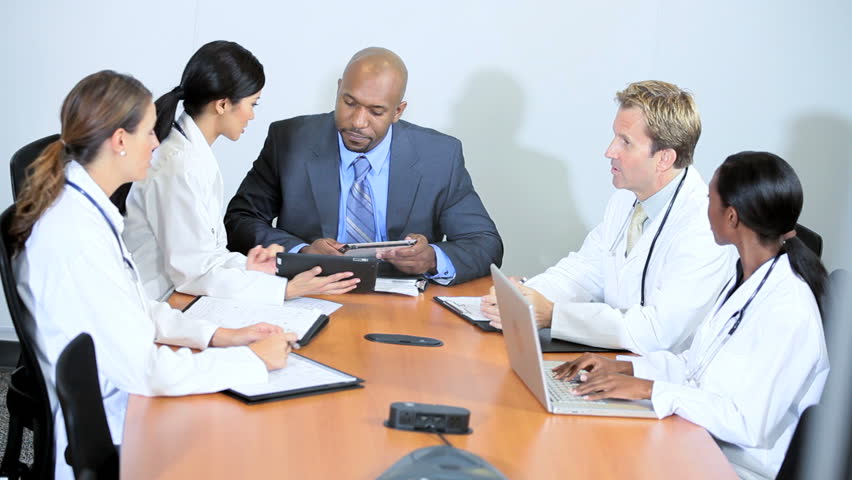 African American financial advisor meeting team medical executives to discuss hospital budgets