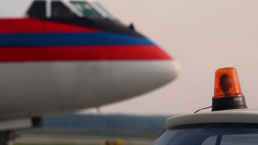 Lamp spins in flasher on roof of car near plane at aerodrome