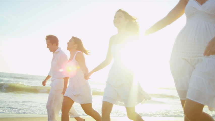 Carefree attractive young Caucasian family happy together on beach vacation sun lens flare shot on RED EPIC