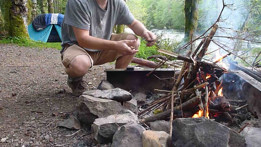 Man starts campfire at camp in the Pacific Northwest, Oregon.
