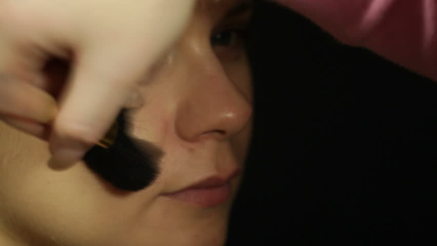 Detail of a young woman applying makeup with brush