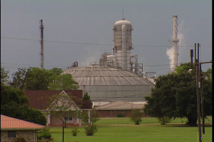 CONVENT, LOUISIANA - SEPTEMBER 4, 1999: Camera pans across smokestacks spewing smoke from Convent oil refineries and chemical plants along River Road.