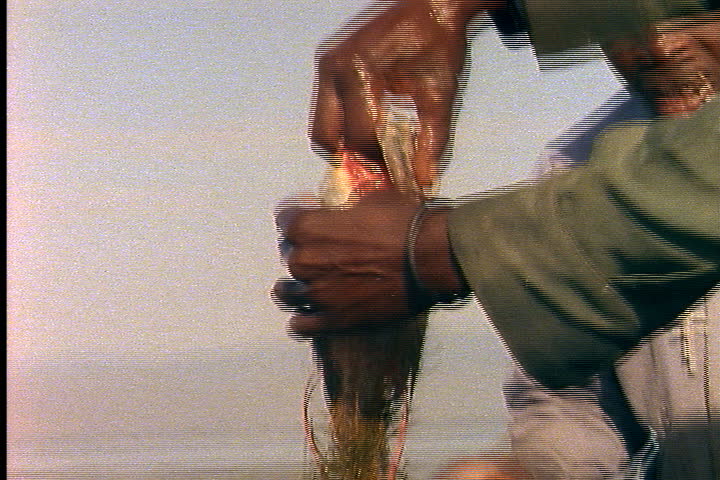 KENYA - MARCH 06, 1989: Two men extract fish from nets.