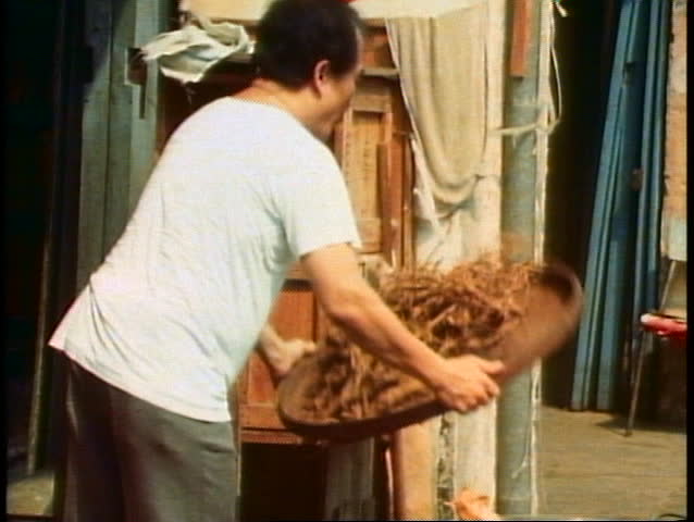 Man tosses rice in a basket to remove chafe in a Singapore market