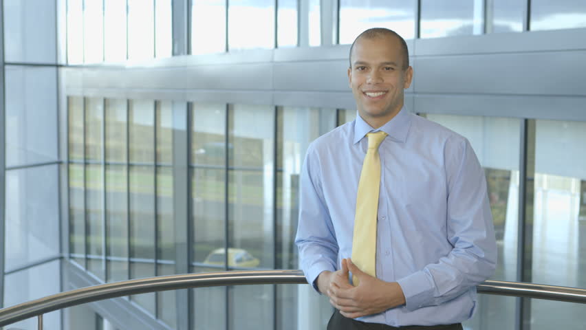 Portrait of an attractive and successful businessman of mixed race ethnicity. He is looking out at the view from his modern, glass office building.