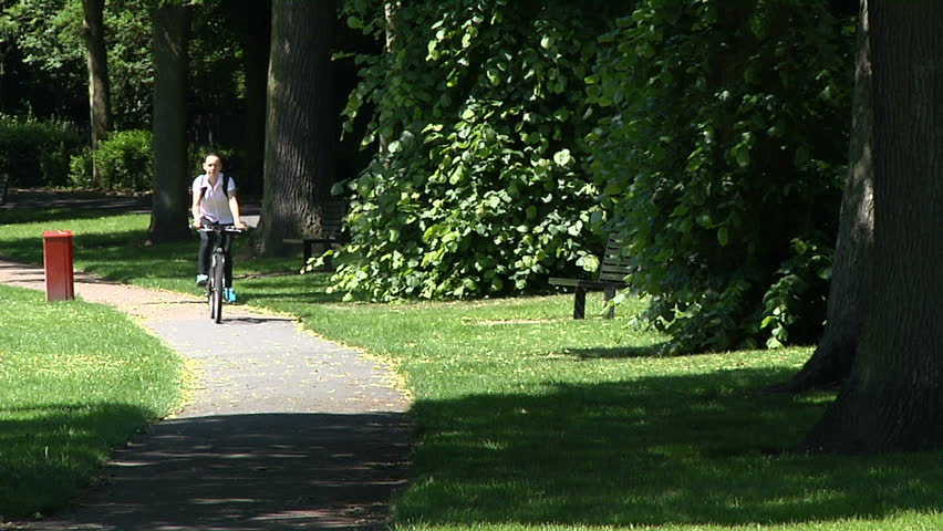 A student cycling along a path with trees