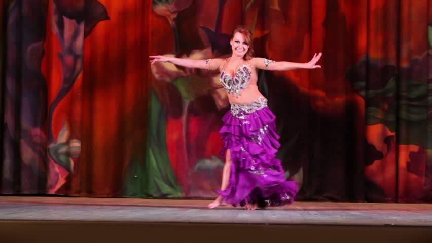 MOSCOW - JAN 28: Red hair woman in magenta skirt and bra embroidered with shiny stones dances on stage of Red October Culture Palace, Jan 28, 2012, Moscow, Russia.