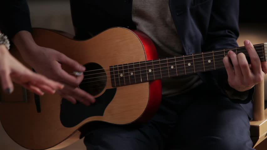 Charismatic girl singing in the studio accompanied by two guitarists