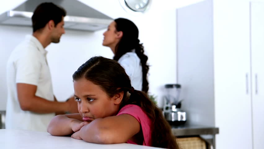 Little girl feeling sad as parents fight at home in kitchen