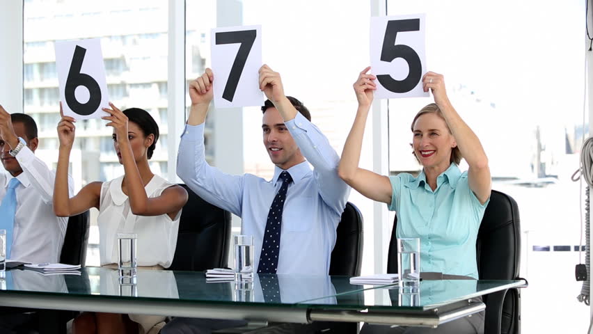 Business people holding grades and showing them in bright office