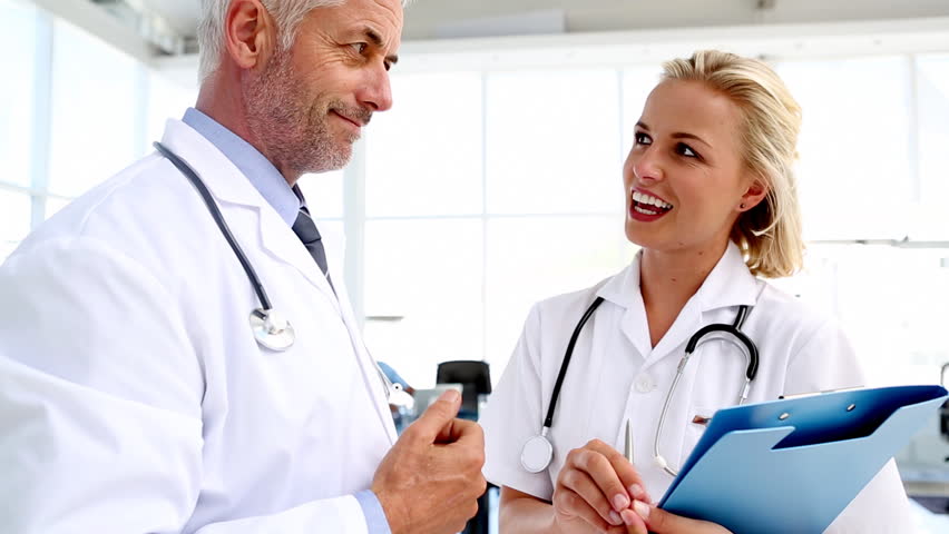 Doctors discussing and writing on a folder in meeting room