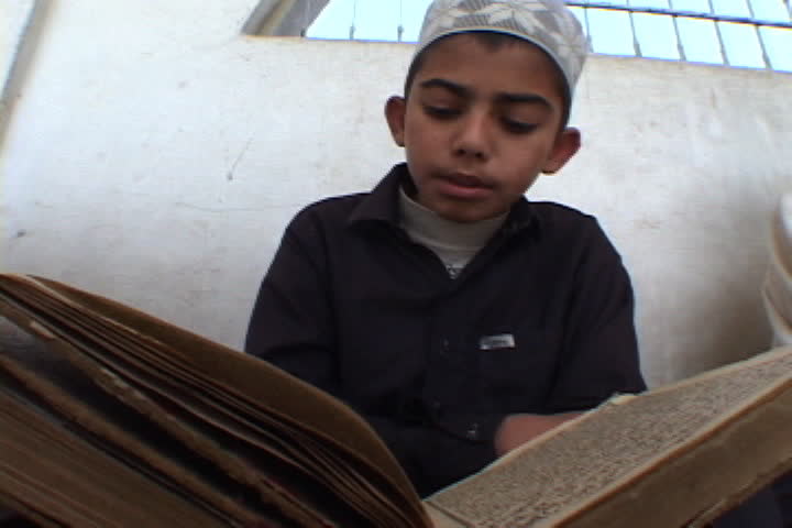 PESHAWAR, PAKISTAN - NOVEMBER 01, 2001: Boy in Muslim dress rocks back and forth as he reads the Koran.