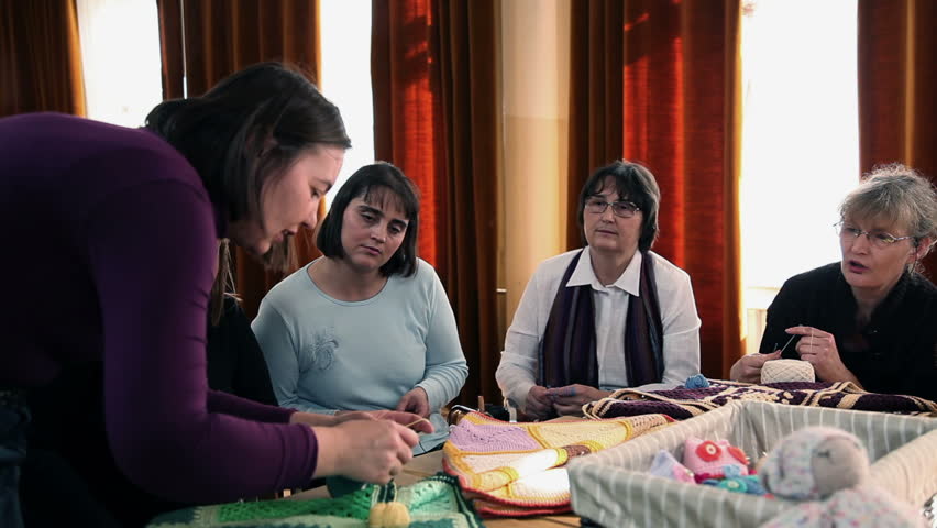 Teacher is demonstrating basics of knitting to the course participants