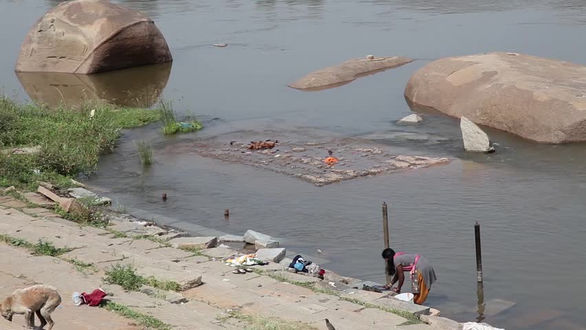 India, Hampi - 30 December 2012: Woman hand washes clothes by the river.