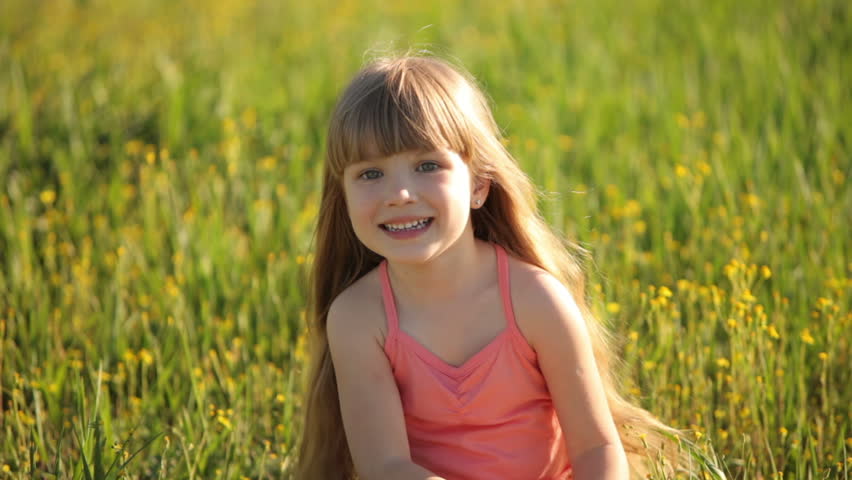 Cute girl sitting in field with flowers

