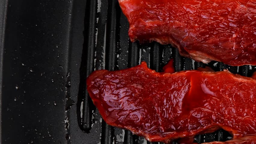 fresh raw bloody beef steaks on black grill plate 1920x1080 intro motion slow hidef hd