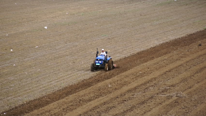 HEILONGJIANG PROVINCE, CHINA - CIRCA MAY 2013: 
Tractor plowing the field (05). Chinese farmer on a small tractor plowing a field in spring day. Tracking shot. North China, Heilongjiang Province, May 2013.