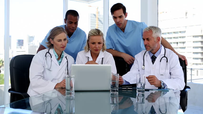 Group of doctors using a laptop together in a meeting room