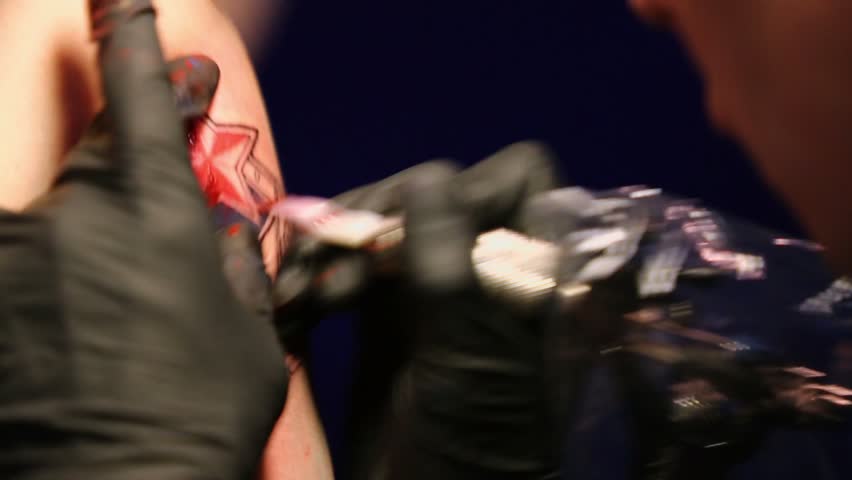 Artist makes football club fan tattoo on mans arm, closeup