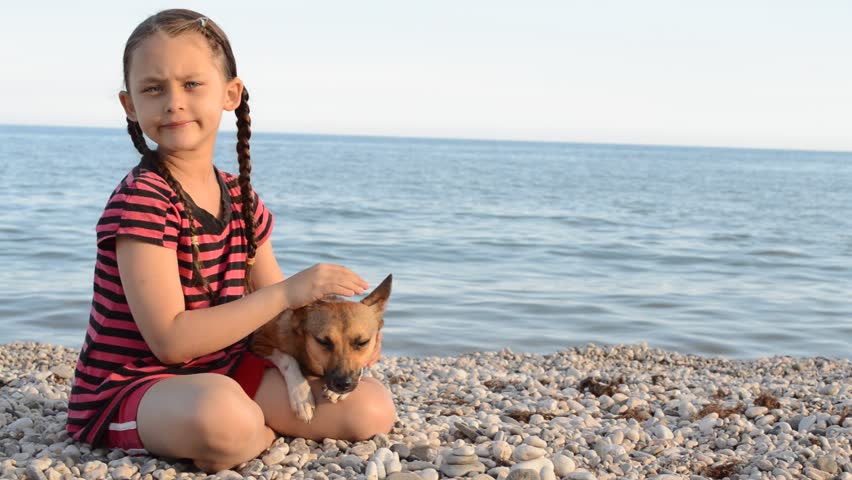 Girl playing with a dog on the sea beach
