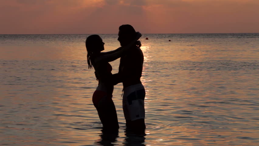 Silhouette Of Romantic Couple Kissing In Sea
