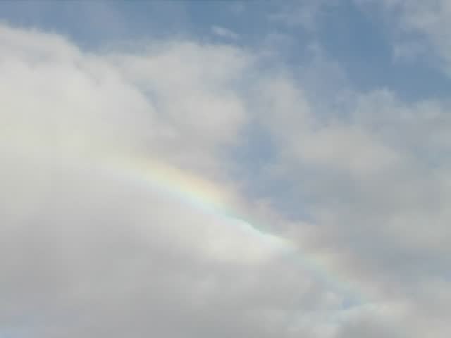 Time lapse of rain clouds clearing to a blue sky with a rainbow in between