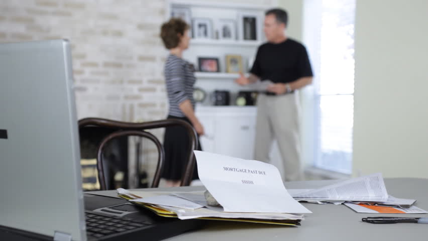 A couple quarreling about finances. Laptop main focus, people out of focus.