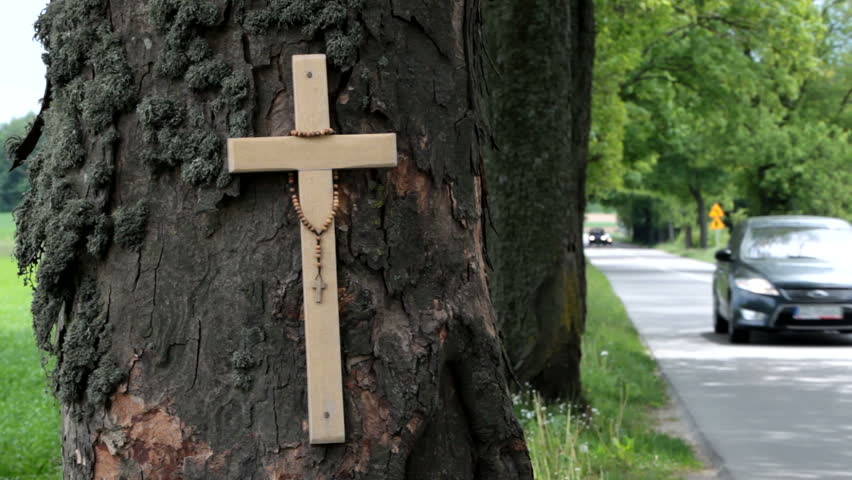 Car overtakes a van on a dangerous narrow country road. Cross and rosary on the side mean that somebody died in road accident.