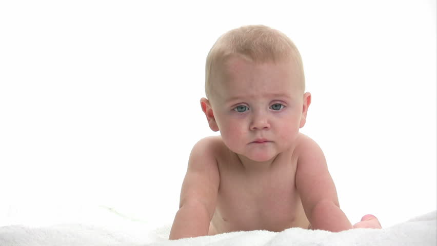 Baby laying on a white towel playing, isolated on white