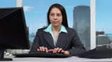 Young business woman typing on PC and taking a phone call - skyline background