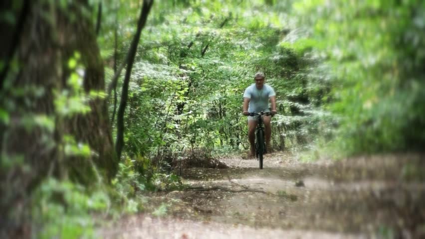 Bicyclist riding down in the forest - "blur efect"