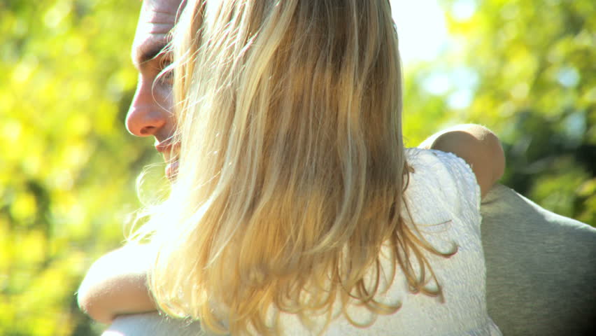 Young father tenderly holding his daughter while outdoors on a summers day