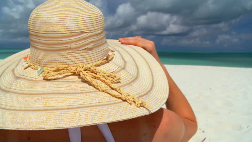 Elegant young female relaxing on white sandy beach looking at aquamarine waters 60 FPS