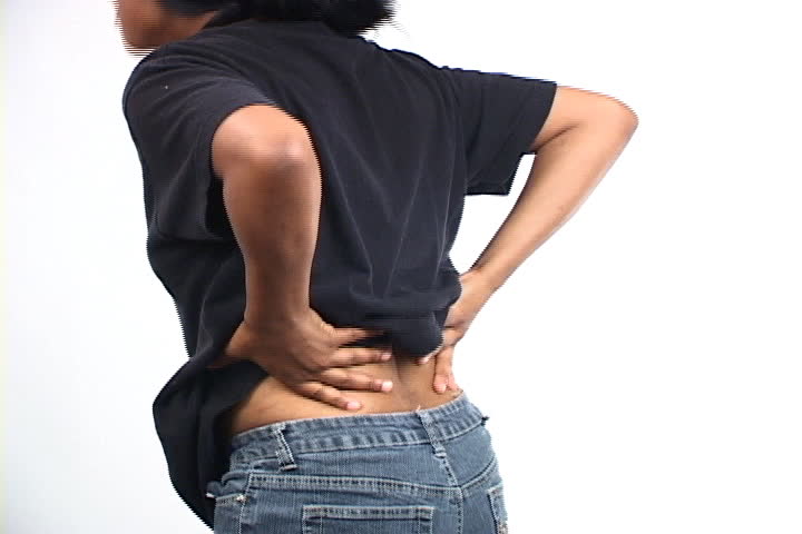 African American woman with backache rubs her back in pain. Shot on miniDV from tripod.