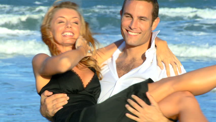 Two young people in love having fun on the beach early morning after a social night out 60 FPS