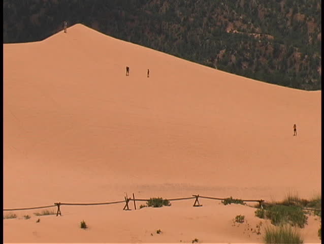 Tourists having fun running down a steep dune in the Coral Pink Sands State Park in southern Utah.